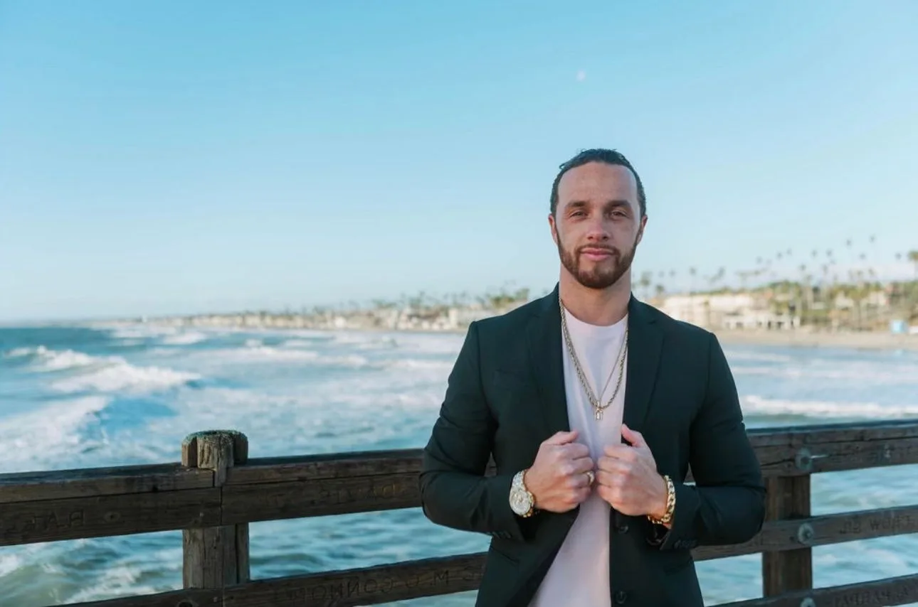 Rudy Perez Jr. standing by the ocean in a black blazer