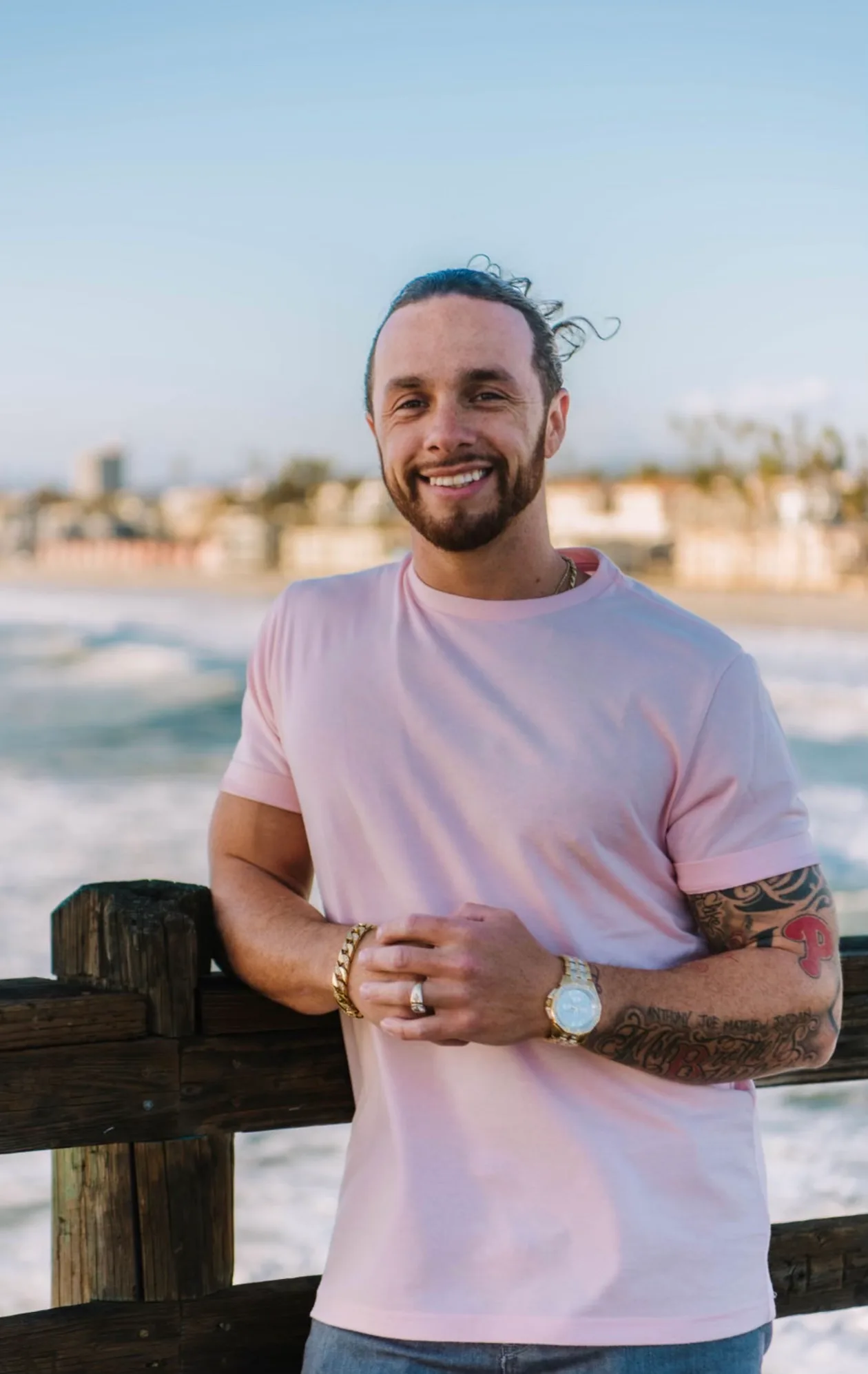 Rudy Perez Jr. smiling, leaning on a railing by the ocean